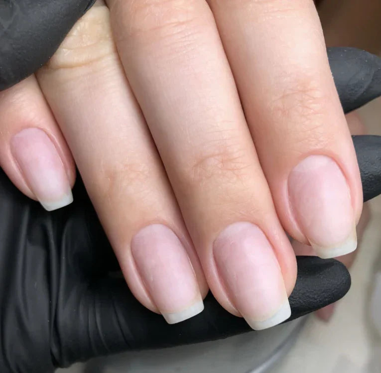 Professional nail technician applying SNS dip powder nails at Bela Beauty College